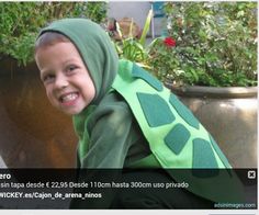 a little boy dressed up like a tortoise shell sitting next to a potted plant