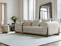 a living room with a white couch and mirror on the wall next to a large window