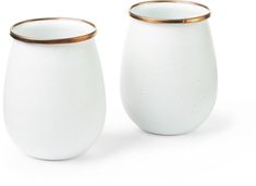 two white vases with gold rims sitting side by side on a white surface