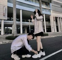 a man kneeling down next to a woman in front of a building with palm trees