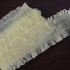 a piece of white fabric with ruffles on it sitting on top of a table