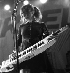 a woman standing in front of a keyboard on stage