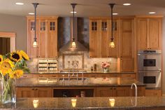 a kitchen with sunflowers in a vase on the counter and lights hanging from the ceiling