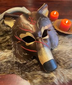 a mask with horns and candles on a fur rug in front of a wooden table