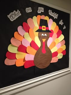 a turkey with a pilgrim hat on it's head hanging from a bulletin board