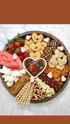 a wooden platter filled with heart shaped cookies, pretzels, strawberries and other snacks