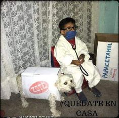 a young boy sitting on top of a chair next to a dog wearing a face mask