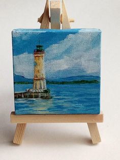 a miniature easel with a painting of a light house on it's side