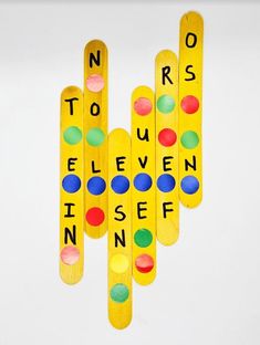 four wooden pegs with different colored dots on them and words written in black ink