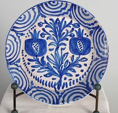 a blue and white plate sitting on top of a wooden stand next to a wall