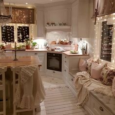 a kitchen filled with lots of white furniture and christmas lights on the windows sill