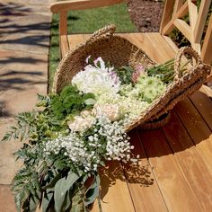 a basket filled with flowers sitting on top of a wooden floor next to a chair