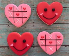 three heart shaped cookies with crosses and hearts painted on them, sitting on a wooden surface