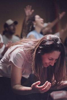 a woman laying on the ground with her hands up in front of her face and other people behind her