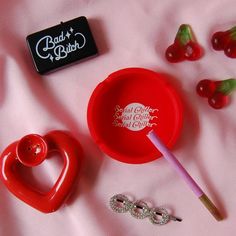 a red bowl and some candy on a pink surface