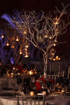 the table is set with wine glasses, candles and a tree decorated with ornaments on it