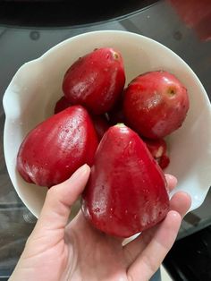 a person holding a white bowl filled with red fruit