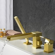 a gold faucet sitting on top of a bath tub next to a bottle