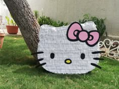 a cardboard hello kitty sitting under a tree