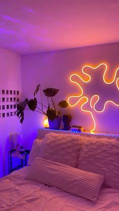 a bed with white sheets and pillows in a room with purple lights on the wall