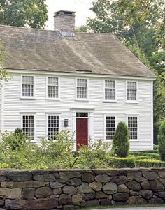 a large white house with a red door and two windows on it's side