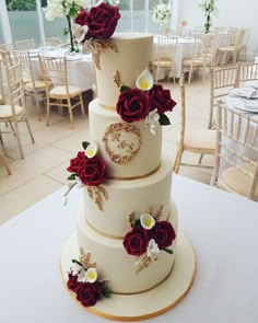 a three tiered wedding cake with red roses on the top and white flowers on the bottom