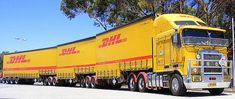 a large yellow truck is parked on the side of the road in front of some trees