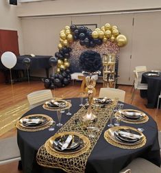 a black table with gold plates and balloons