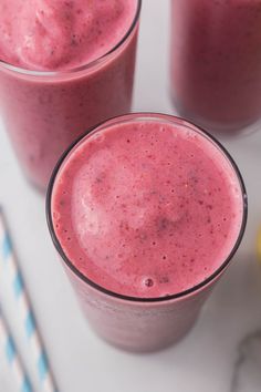 two glasses filled with pink smoothie next to lemons