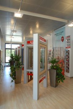 the interior of a building with plants in planters on display and posters on the walls