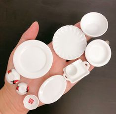 a hand holding several white dishes and plates