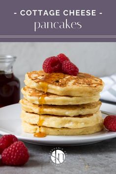 a stack of pancakes with syrup and raspberries on the side