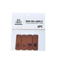 four pieces of brown leather labels with black lettering on the front and back of them