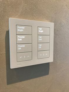 the control panel on the wall is white and has buttons for different types of electrical devices