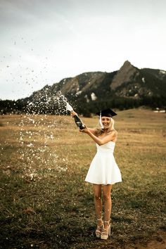 a woman in a white dress is spraying water on her head with a bottle and an umbrella