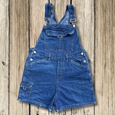 These blue jean overalls by No Boundaries are in good preowned vintage condition! Check out all photos to see. Carpenter style pockets. Tag Size is Medium in JRs but, check out measurements below to ensure an accurate fit Comes from a smoke free home Fast handling time for faster shipping Measurements taken laid flat and in inches Waist: 15.5 inches (31 inches around) Rise: 12 inches Hips: 20 inches (40 inches around) Leg Opening: 12 inches (24 inches around) Inseam: 3 inches Cheap Vintage Denim Blue Overalls, Cheap Denim Blue Cotton Shortalls, Dark Blue Overalls, Blue Jean Overalls, Overalls Shorts, Blue Overalls, Jean Overalls, Shorts Summer, Summer Blue