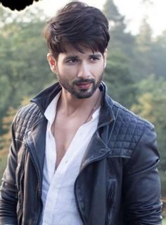 a man with a goatee and leather jacket on posing for a photo in front of trees