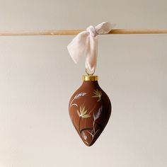 an ornament hanging from a clothes line with a bow on it's end