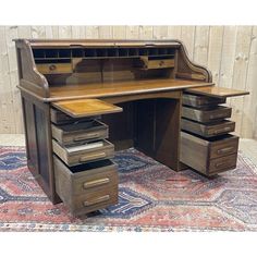 an old wooden desk with drawers on top and a rug in the foreground next to it