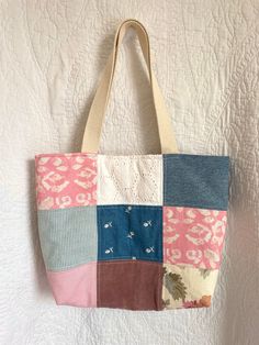 a multicolored patchwork tote bag hanging on a wall