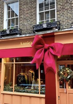 a store front with a large pink bow on it