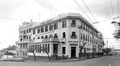 an old black and white photo of a building on the corner of a street with cars parked in front of it