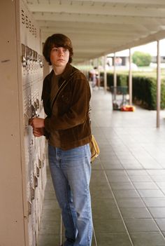 a young man leaning against a wall with his hand on the door