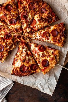 a sliced pizza sitting on top of a piece of wax paper