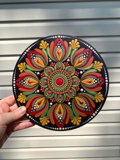 a hand holding up a colorful plate with an intricate design on the front and side