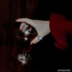 a person holding a wine glass in their hand with sparkling stars on the top of it