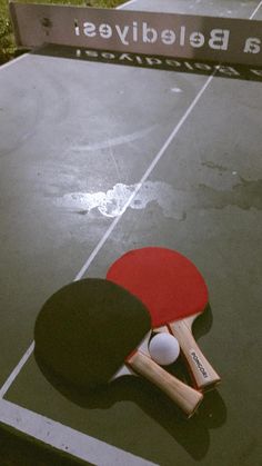 two ping pong paddles on top of a tennis court