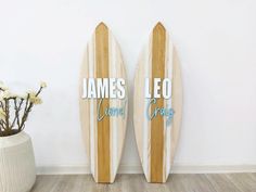 two wooden surfboards with the words james leo and crazy written on them next to a potted plant