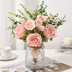 a vase filled with pink flowers sitting on top of a table next to a book