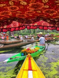 several boats are lined up in the water with flowers on them and people standing around